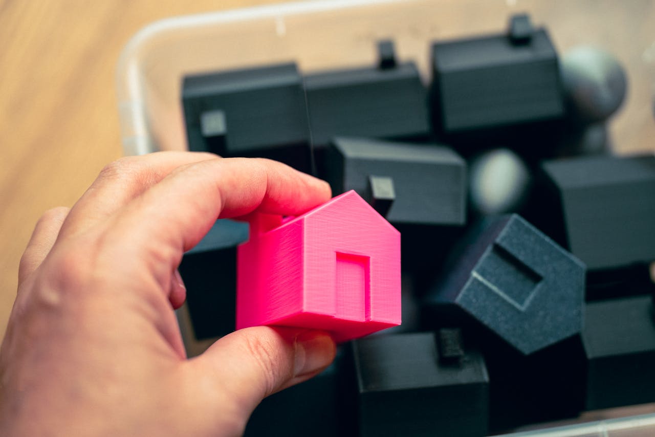 Crafting Captivating Headlines: Your awesome post title goes here Hand selecting a pink house model from a box of miniature homes, symbolizing real estate choices.