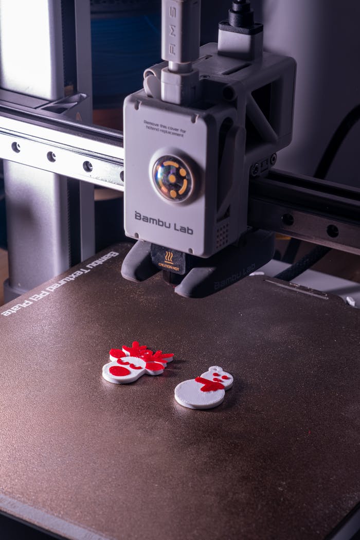 hero-img-01 Close-up of a 3D printer creating vibrant snowman decorations, embodying modern technology and festive spirit.